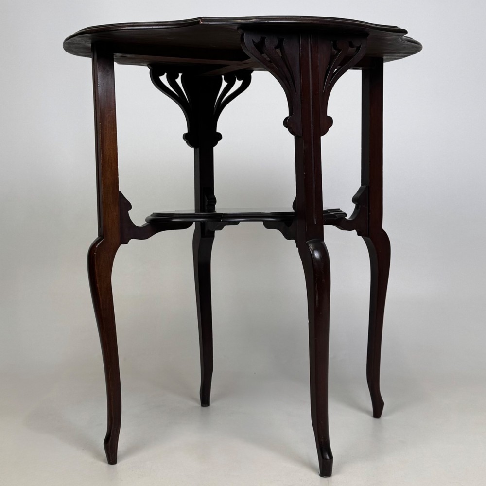 An Edwardian dark mahogany side table featuring a shaped top, pierced carved spandrels, slender cabriole legs, and a lower tier shelf. View III