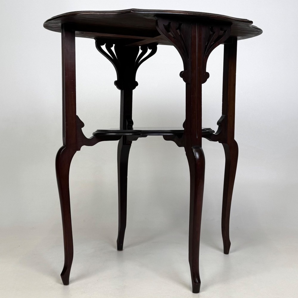 An Edwardian dark mahogany side table featuring a shaped top, pierced carved spandrels, slender cabriole legs, and a lower tier shelf. View VII