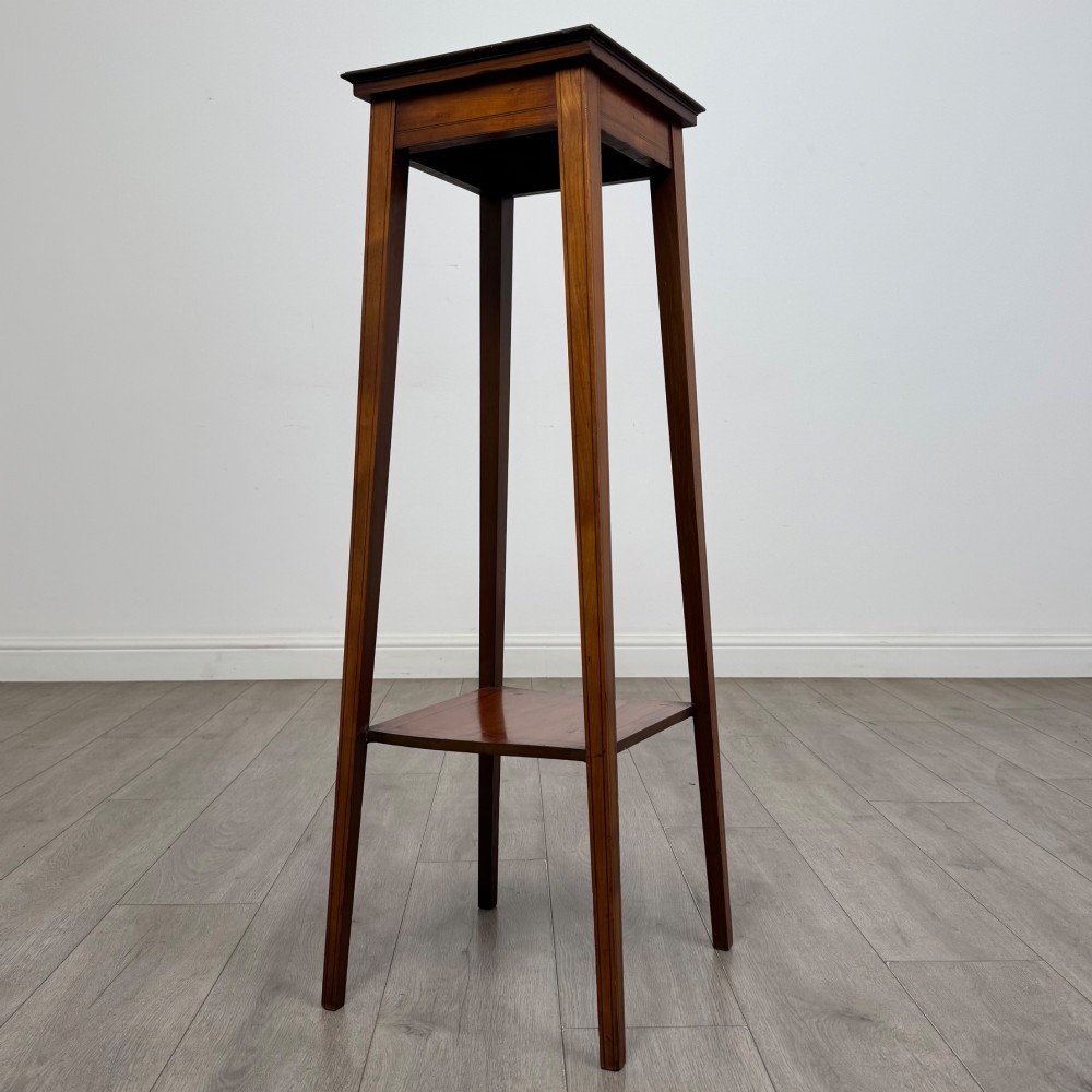 A tall, slender Edwardian satinwood plant stand with square tapered legs, a flat square top, and a lower undertier shelf. View II