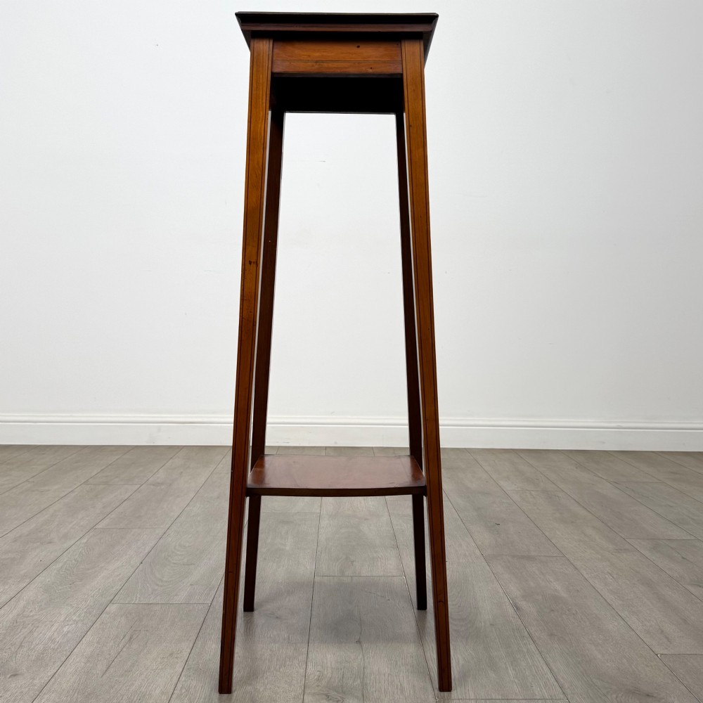 A tall, slender Edwardian satinwood plant stand with square tapered legs, a flat square top, and a lower undertier shelf. View V