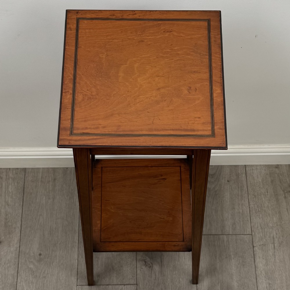 A tall, slender Edwardian satinwood plant stand with square tapered legs, a flat square top, and a lower undertier shelf. View VII