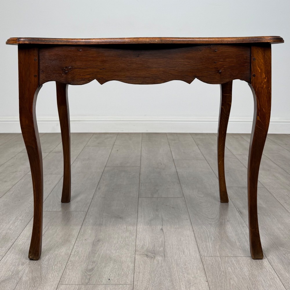 A French provincial oak side table with curved cabriole legs and a scalloped apron.