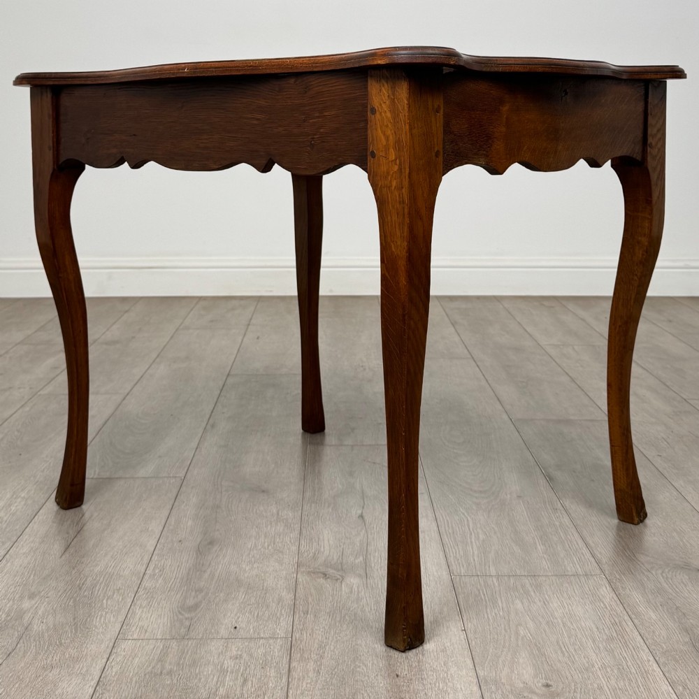 A French provincial oak side table with curved cabriole legs and a scalloped apron. View II