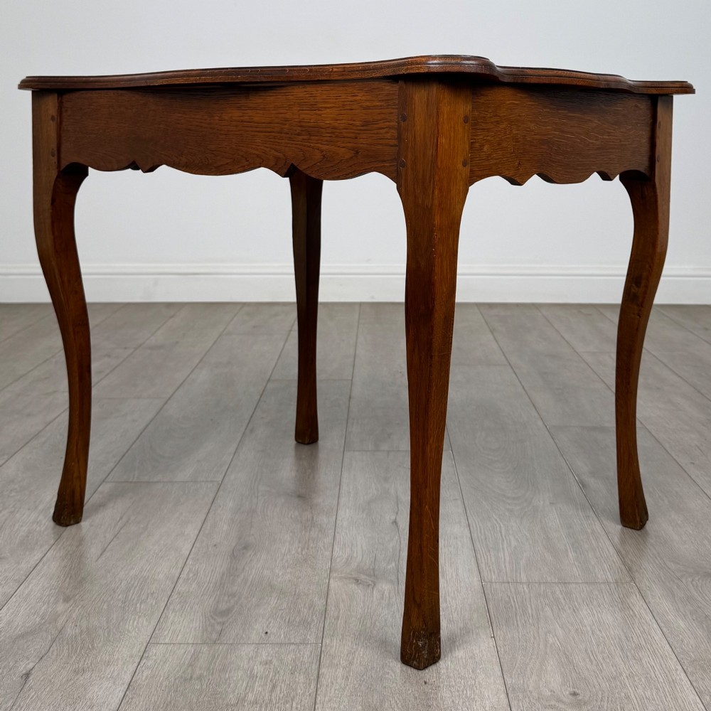 A French provincial oak side table with curved cabriole legs and a scalloped apron. View VI