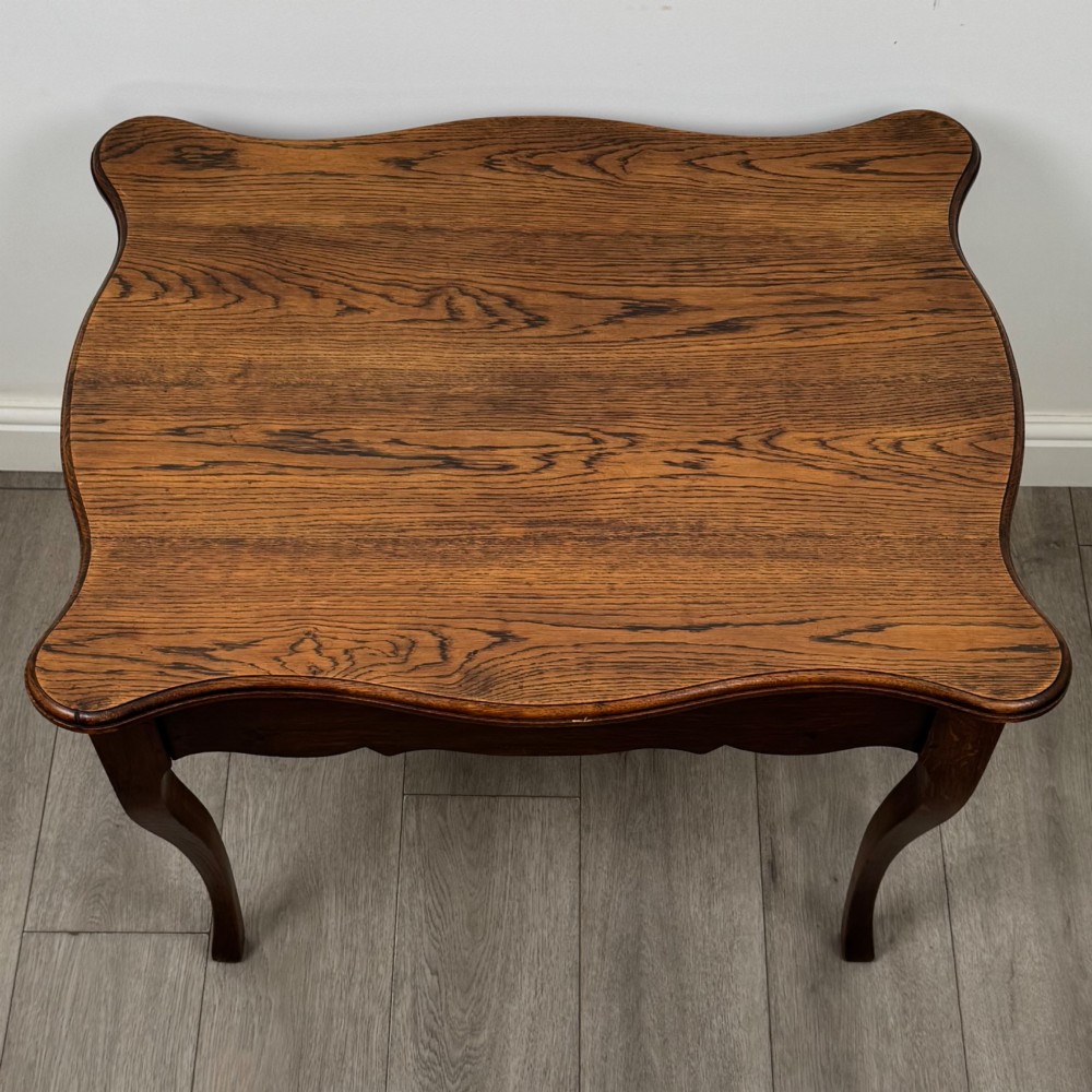 A French provincial oak side table with curved cabriole legs and a scalloped apron. View IX
