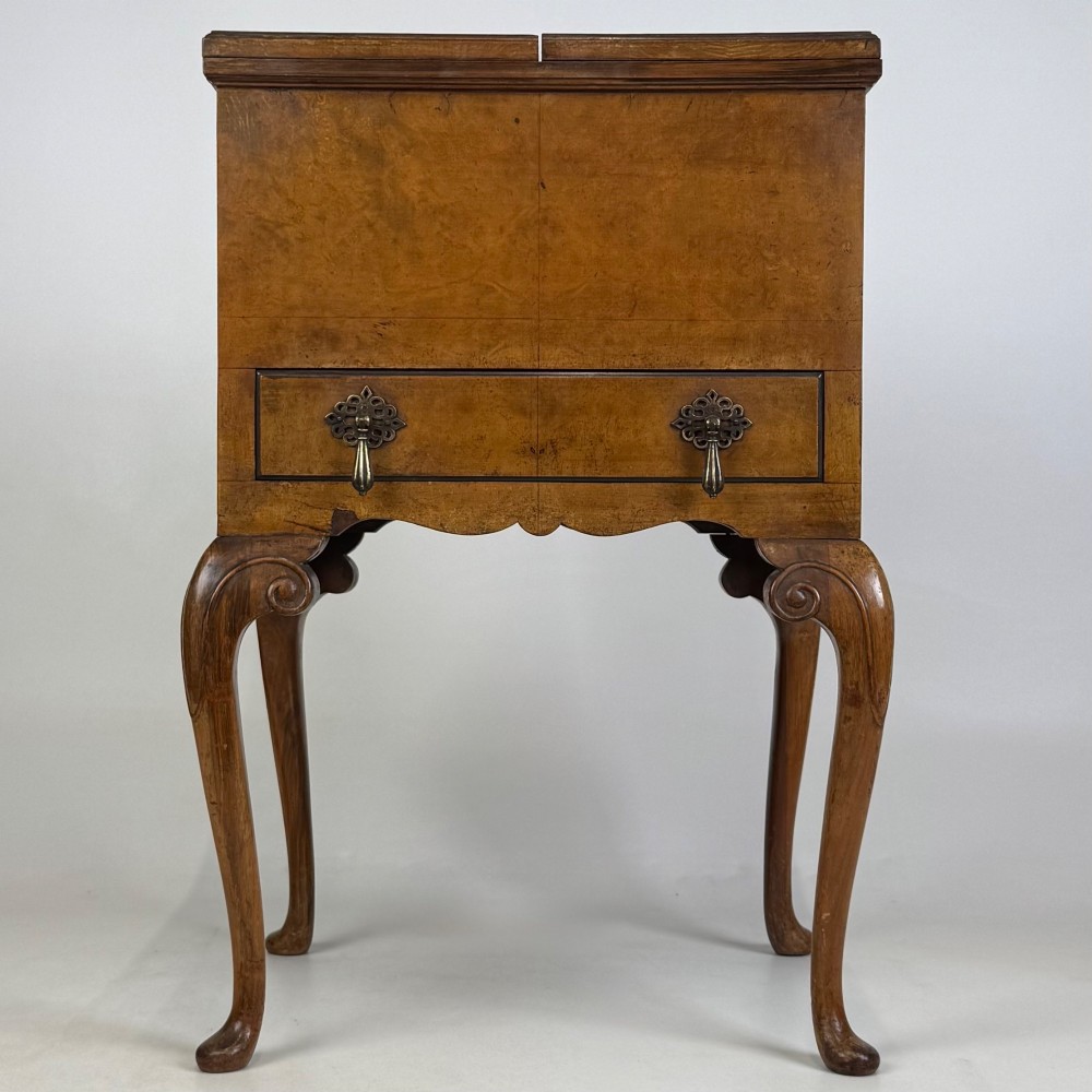 An Edwardian burr walnut cabinet resting on slender cabriole legs with ornate brass drop handles.