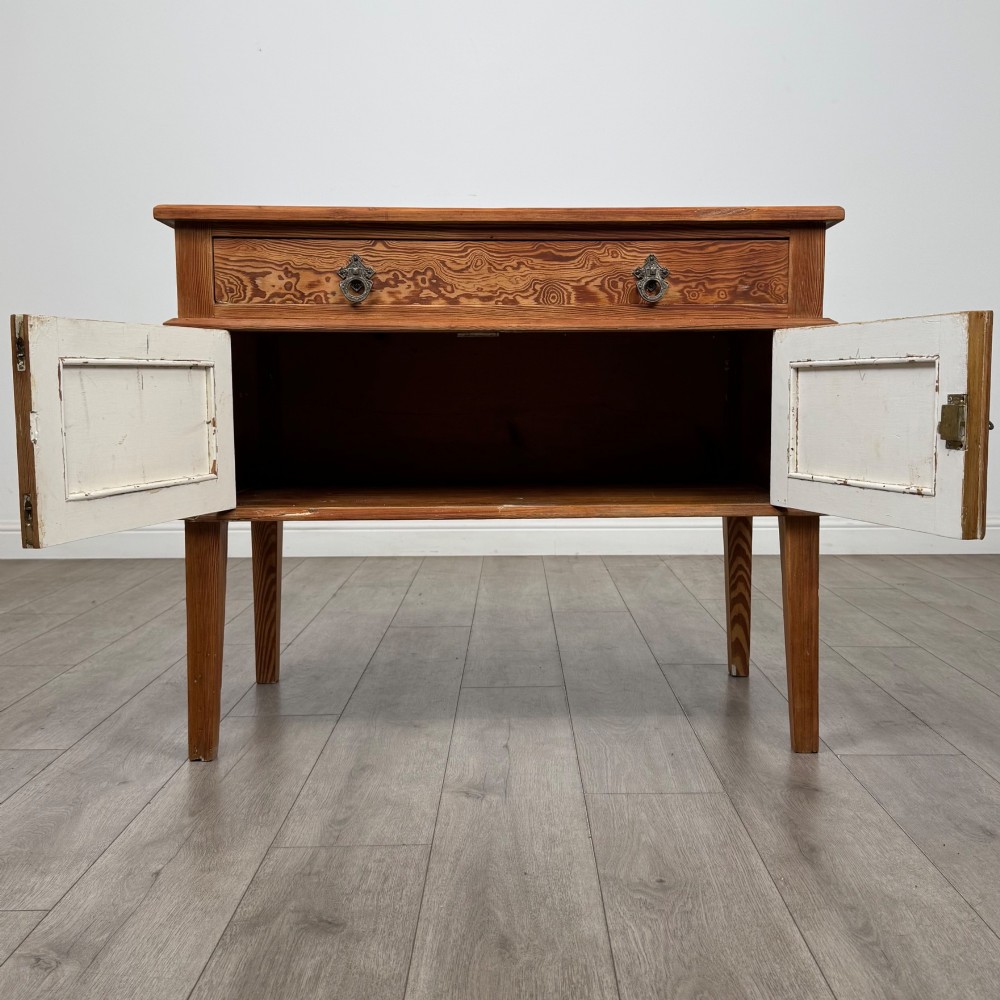 A Victorian pitch pine cupboard featuring a single top drawer over two cupboard doors with diagonal timber panels and straight tapered legs. View II