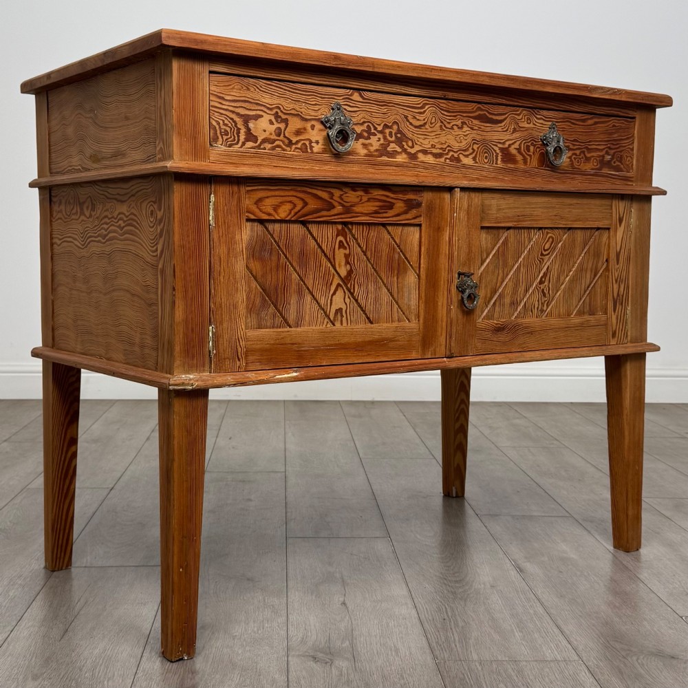 A Victorian pitch pine cupboard featuring a single top drawer over two cupboard doors with diagonal timber panels and straight tapered legs. View IX