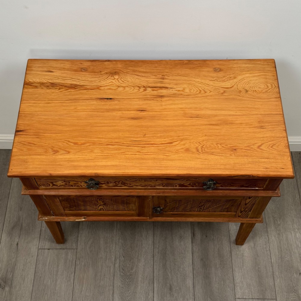 A Victorian pitch pine cupboard featuring a single top drawer over two cupboard doors with diagonal timber panels and straight tapered legs. View X