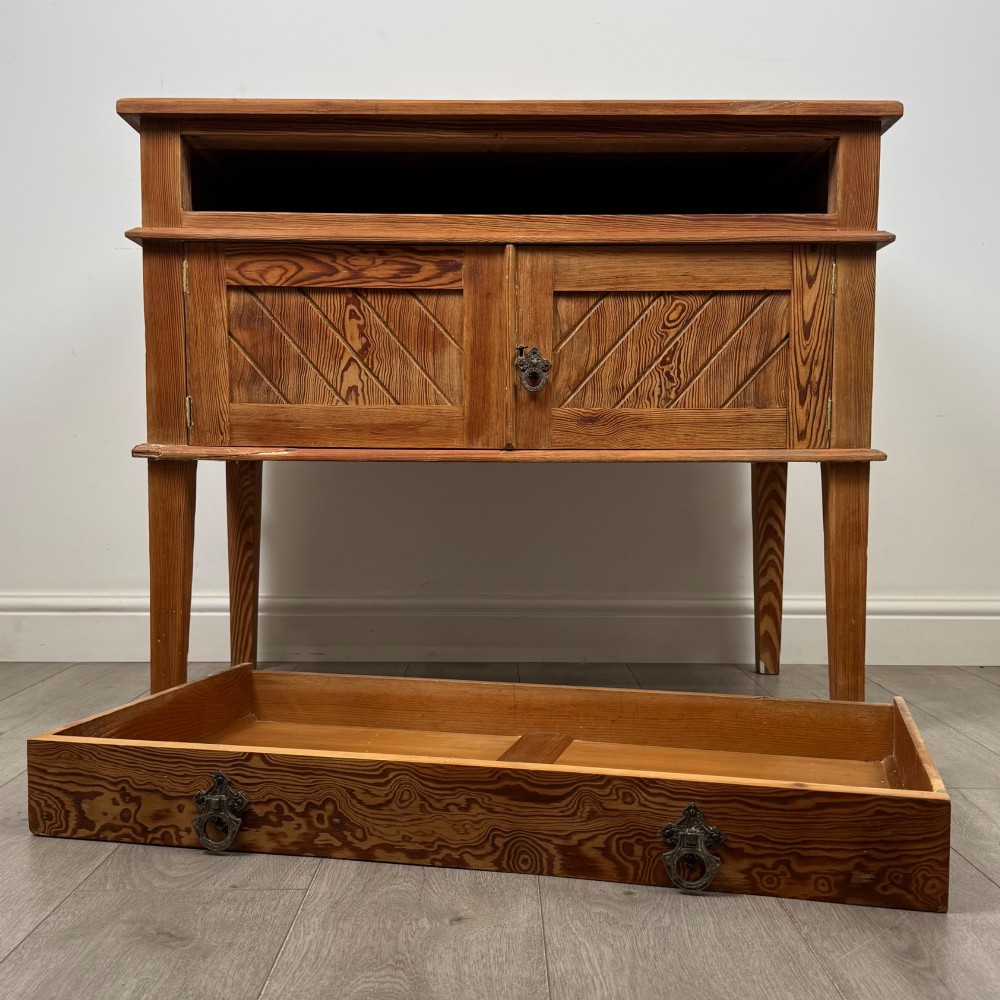 A Victorian pitch pine cupboard featuring a single top drawer over two cupboard doors with diagonal timber panels and straight tapered legs. View XI