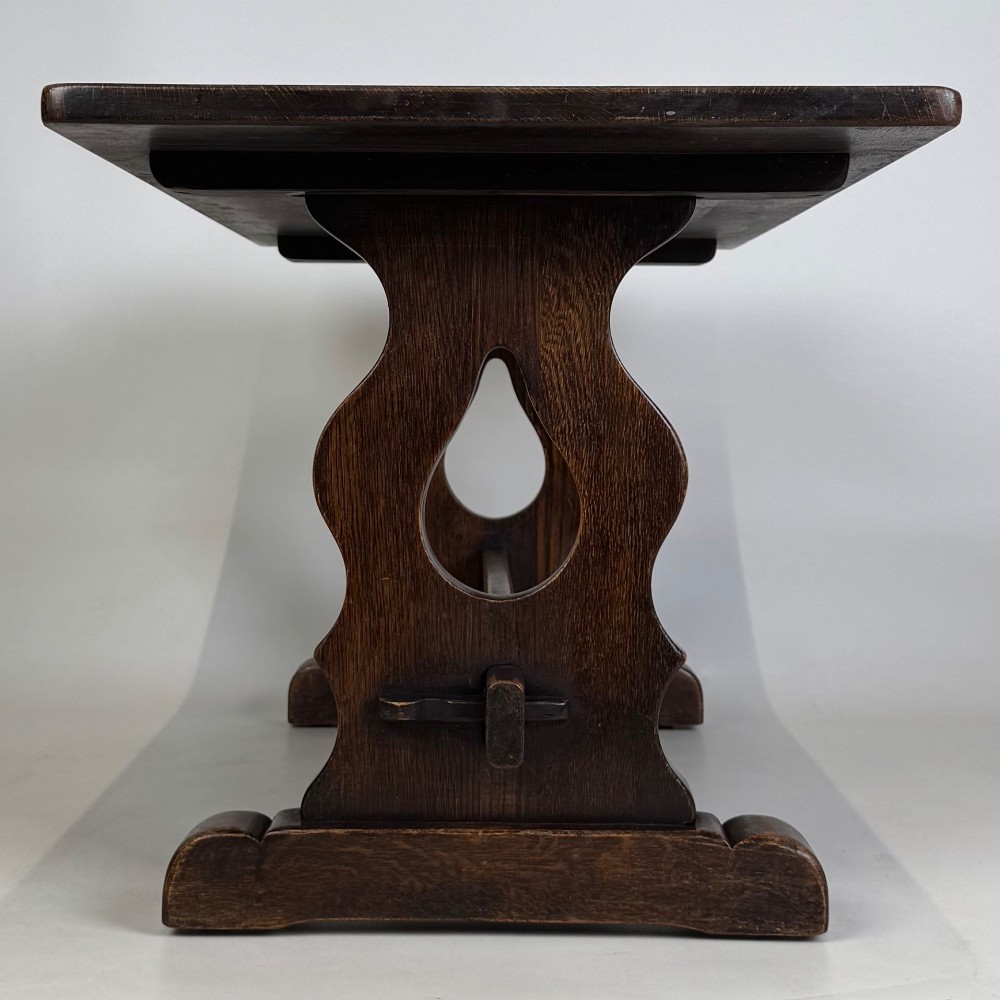 A dark oak trestle coffee table featuring shaped side supports with teardrop cut-outs and a low central stretcher. View III