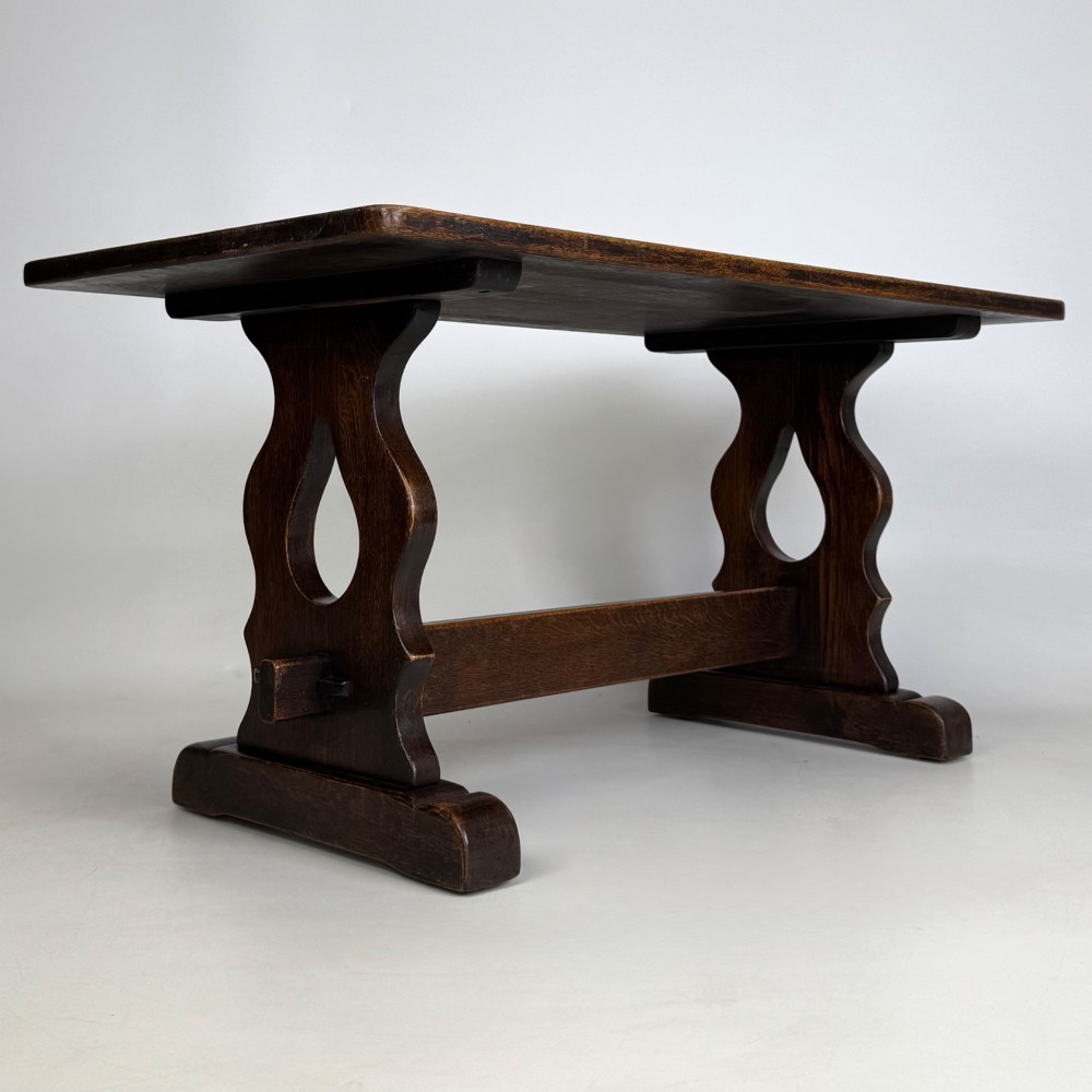 A dark oak trestle coffee table featuring shaped side supports with teardrop cut-outs and a low central stretcher. View IV