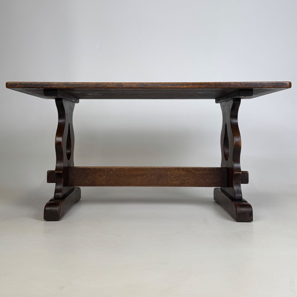 A dark oak trestle coffee table featuring shaped side supports with teardrop cut-outs and a low central stretcher. View V
