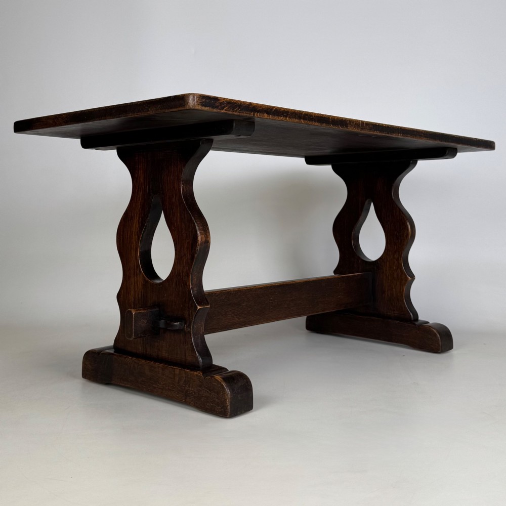 A dark oak trestle coffee table featuring shaped side supports with teardrop cut-outs and a low central stretcher. View VIII