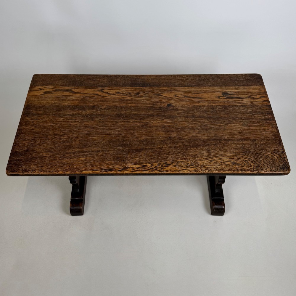 A dark oak trestle coffee table featuring shaped side supports with teardrop cut-outs and a low central stretcher. View IX