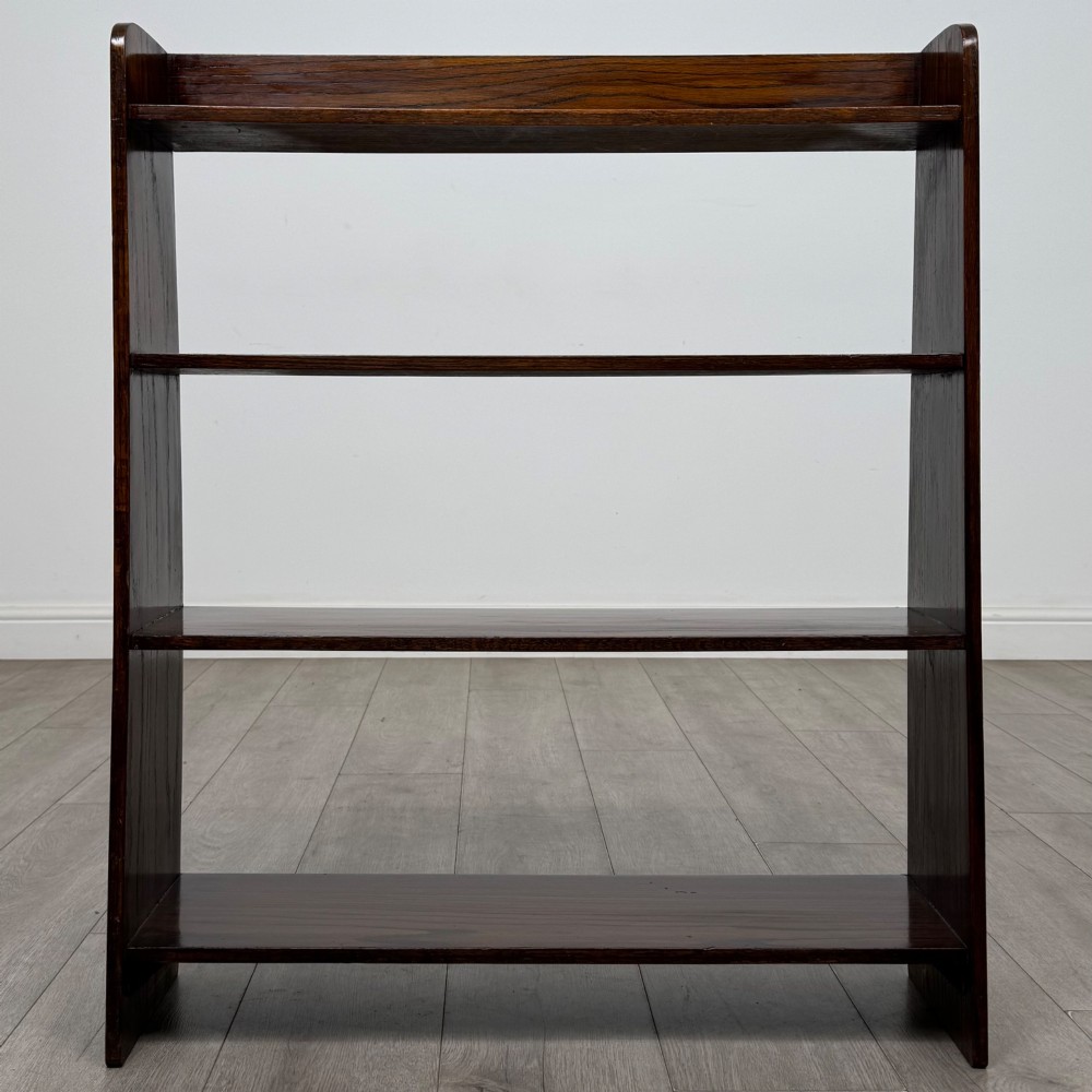 A dark oak Edwardian open bookcase with four horizontal shelves holding leather-bound books. View II
