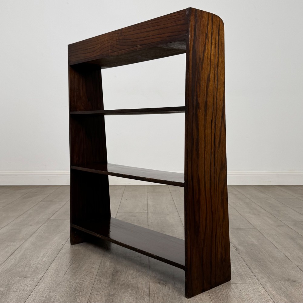 A dark oak Edwardian open bookcase with four horizontal shelves holding leather-bound books. View VII