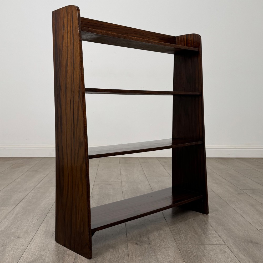 A dark oak Edwardian open bookcase with four horizontal shelves holding leather-bound books. View IX