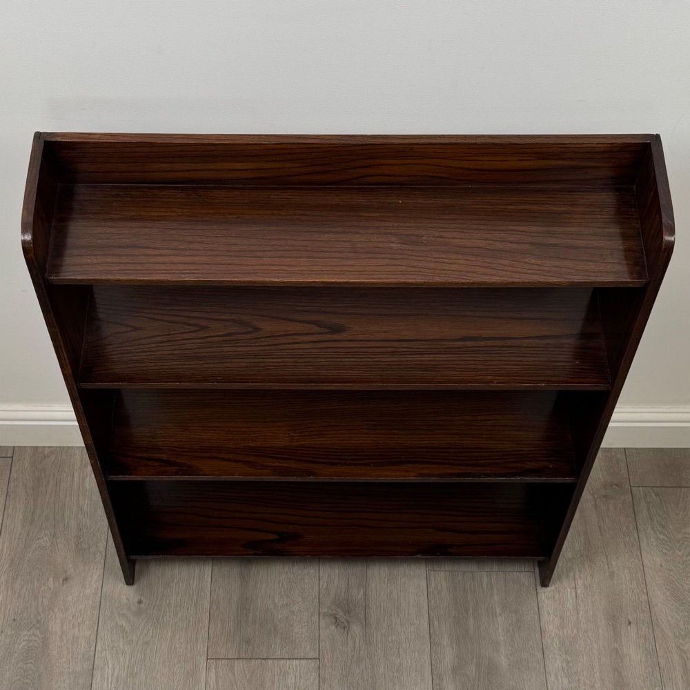 A dark oak Edwardian open bookcase with four horizontal shelves holding leather-bound books. View X