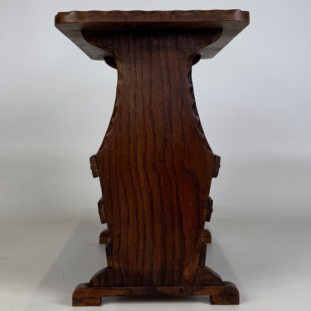 A dark brown oak side table featuring a rectangular top with scalloped carved edges over an integrated three-slat magazine rack below. View III