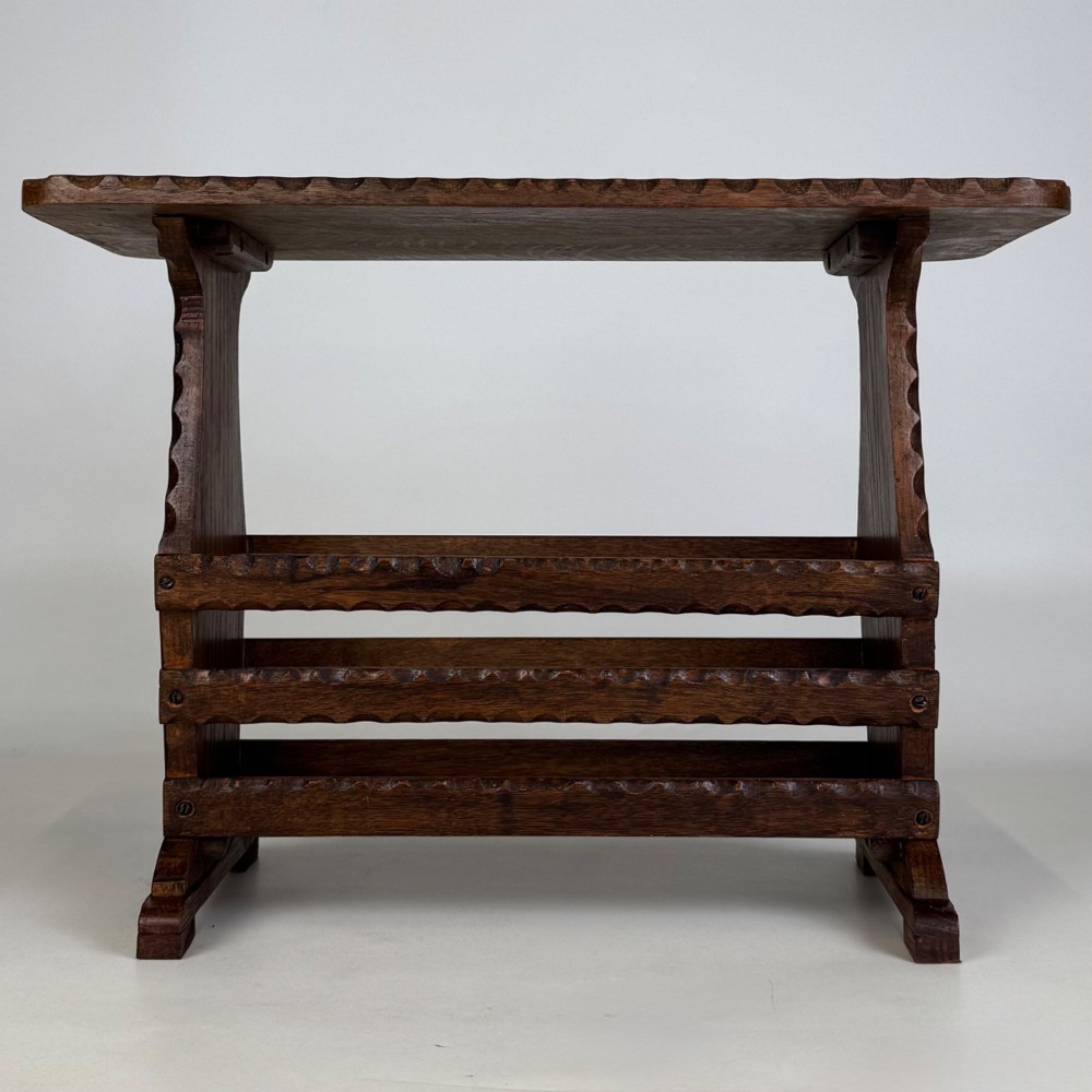 A dark brown oak side table featuring a rectangular top with scalloped carved edges over an integrated three-slat magazine rack below. View V