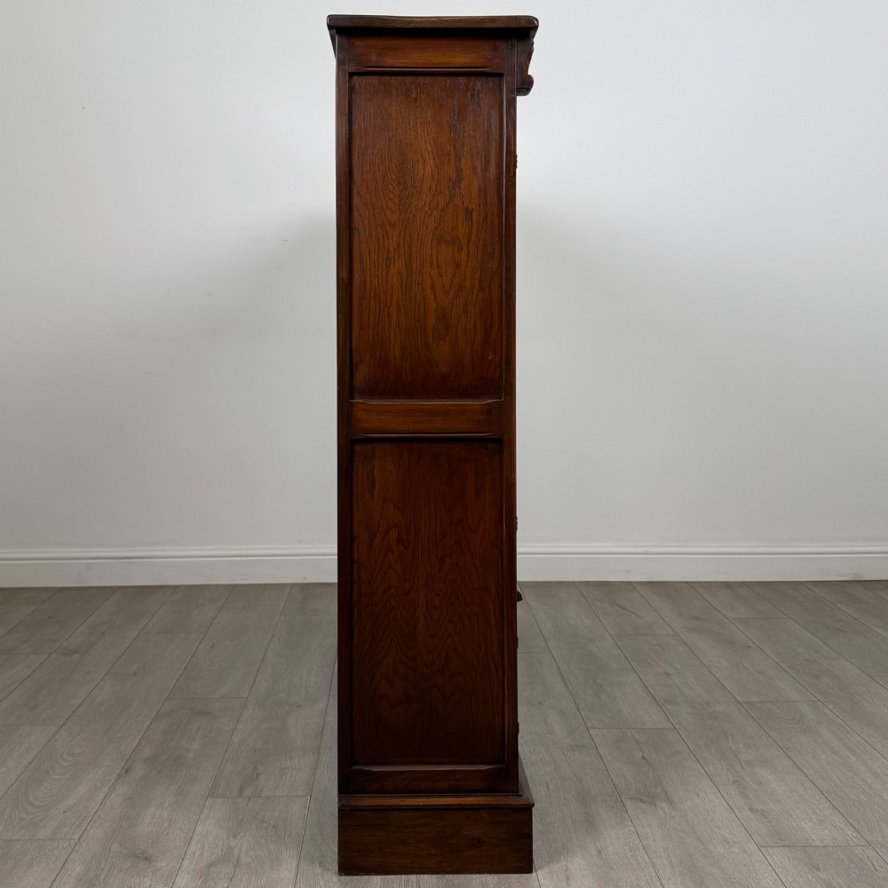 A large dark brown carved oak display cabinet featuring three leaded glass doors over three carved cupboard doors with metal ring pulls. View VIII