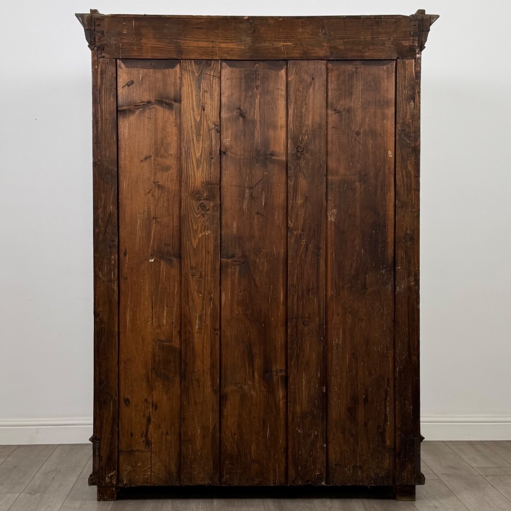 A 19th-century French walnut wardrobe with double doors featuring detailed carved foliate panels, central fluted columns, two lower drawers, and a stepped cornice. View VI