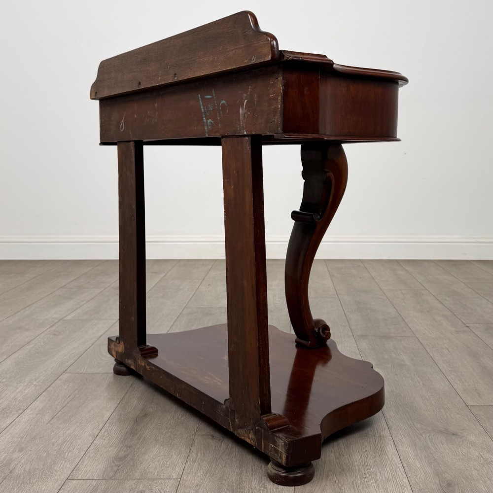 A 19th-century Victorian mahogany washstand featuring a carved central leg, shaped top, and contoured plinth base. View VI