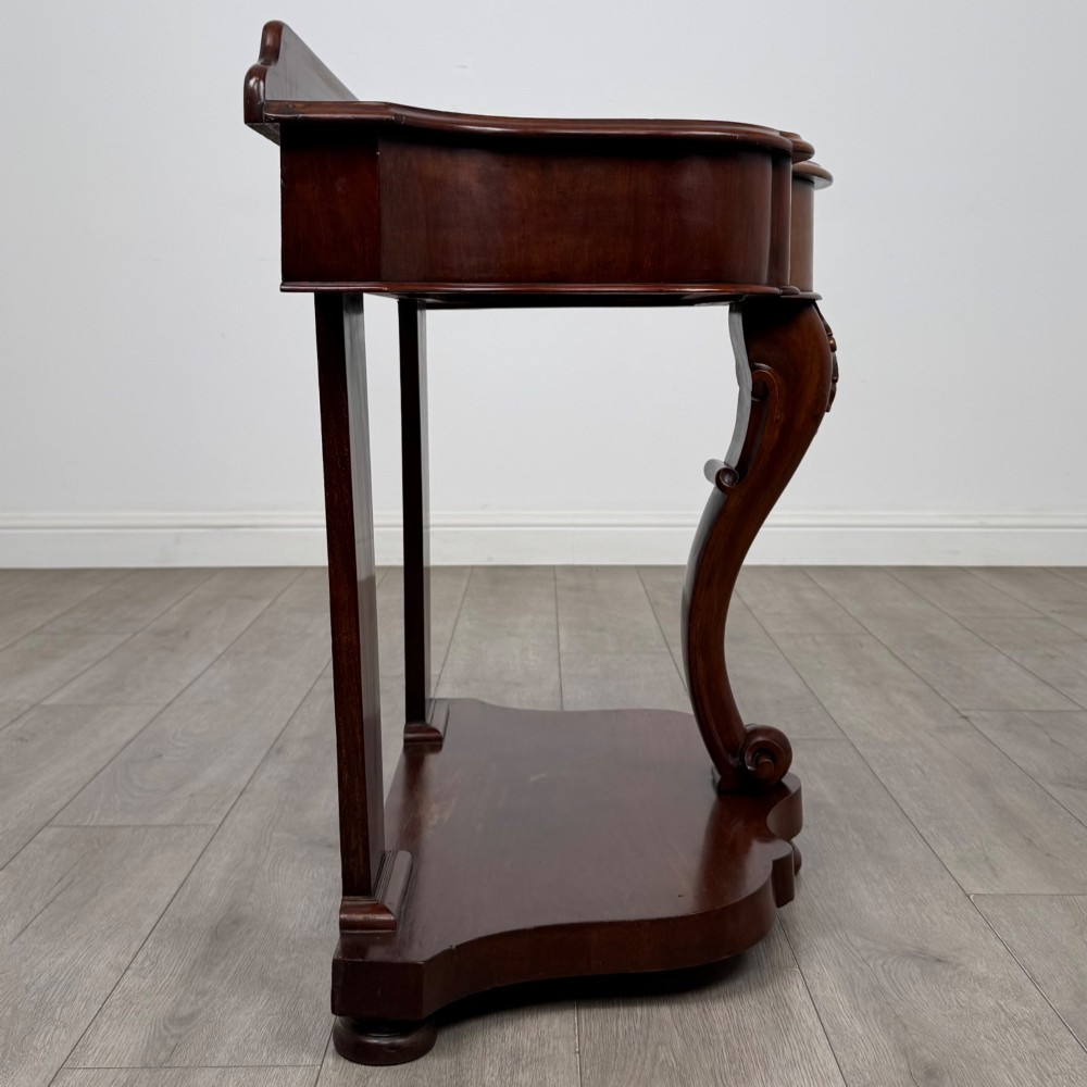 A 19th-century Victorian mahogany washstand featuring a carved central leg, shaped top, and contoured plinth base. View VII