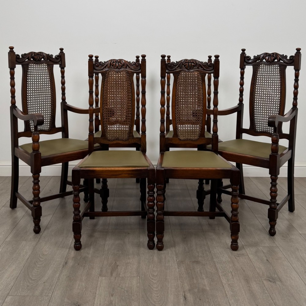 A set of six Victorian oak dining chairs featuring carved crest rails, cane backrest panels, turned legs, and green upholstered seats.