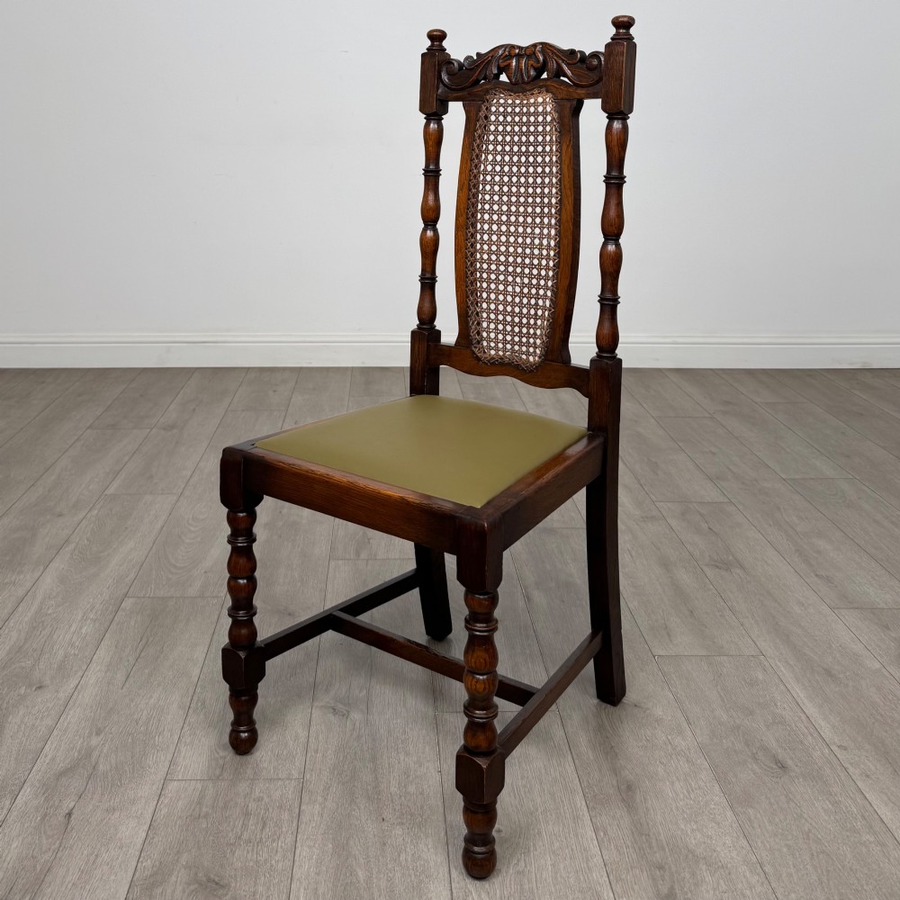 A set of six Victorian oak dining chairs featuring carved crest rails, cane backrest panels, turned legs, and green upholstered seats. View III