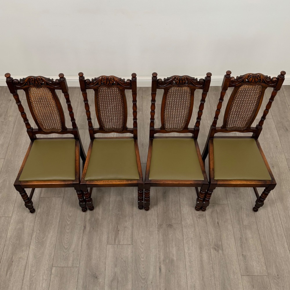 A set of six Victorian oak dining chairs featuring carved crest rails, cane backrest panels, turned legs, and green upholstered seats. View IX
