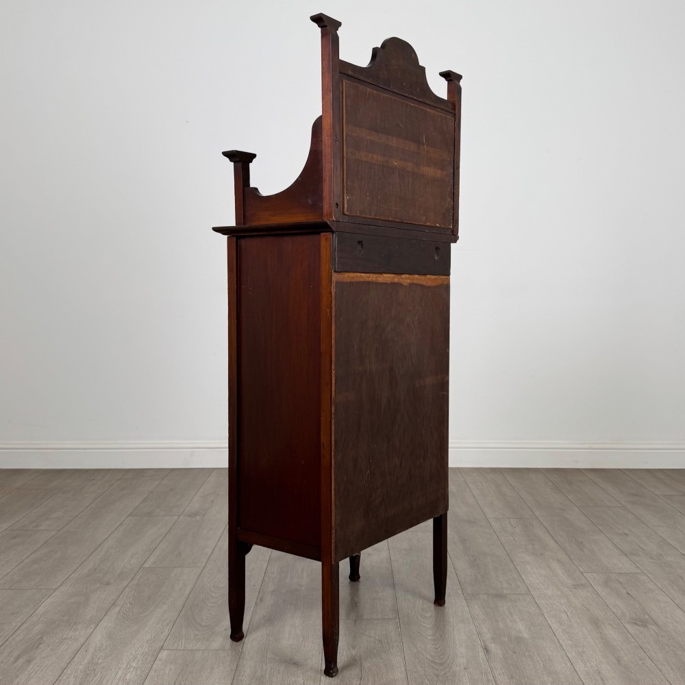 An Edwardian mahogany display cabinet featuring a upper mirrored rail with floral wood inlay above a single glazed door cupboard. View V