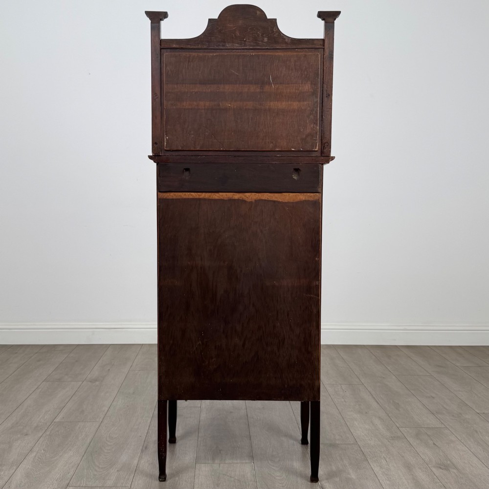 An Edwardian mahogany display cabinet featuring a upper mirrored rail with floral wood inlay above a single glazed door cupboard. View VI
