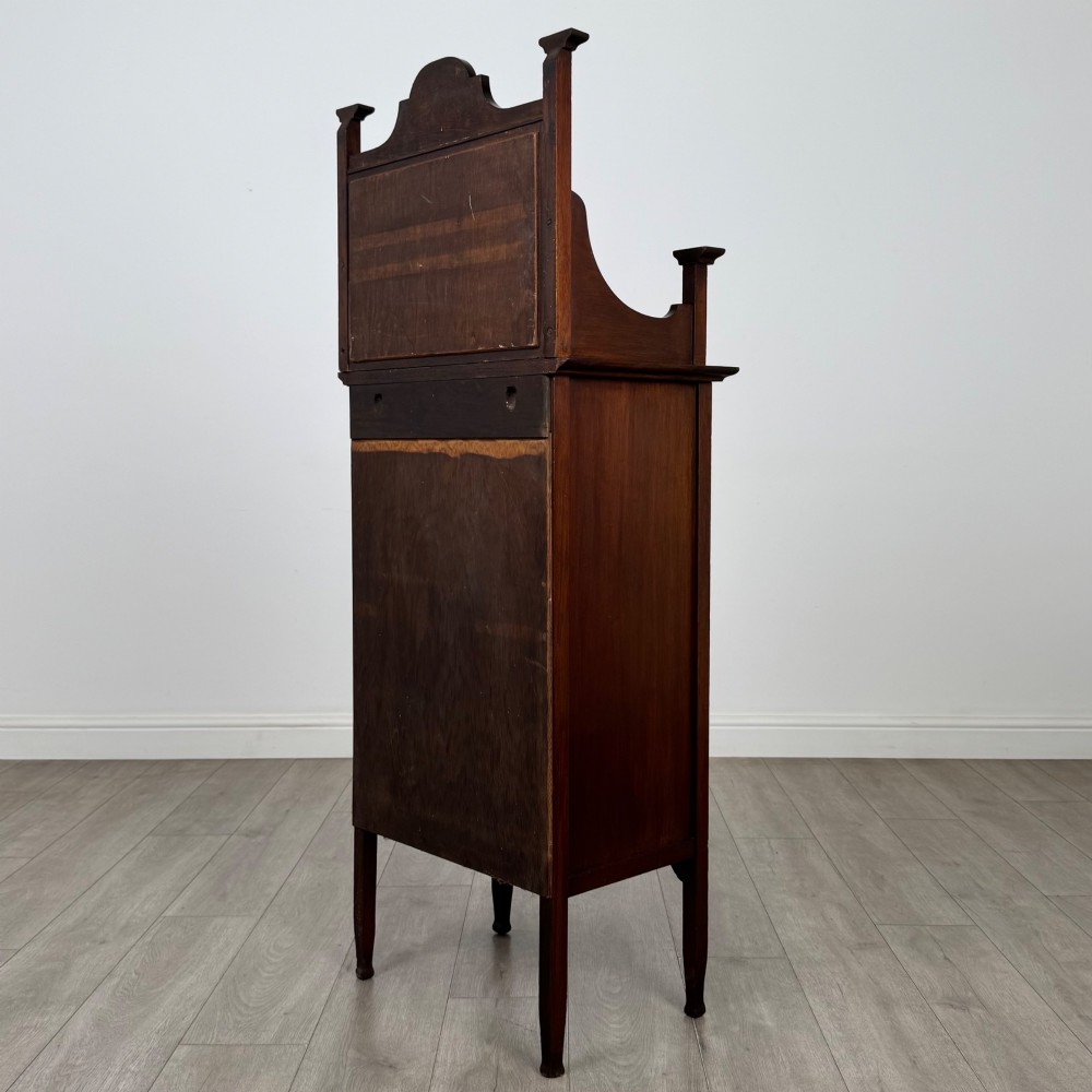 An Edwardian mahogany display cabinet featuring a upper mirrored rail with floral wood inlay above a single glazed door cupboard. View VII