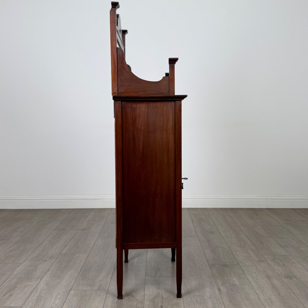 An Edwardian mahogany display cabinet featuring a upper mirrored rail with floral wood inlay above a single glazed door cupboard. View VIII
