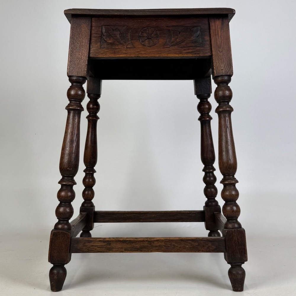 An antique dark oak side table featuring carved rosette apron details, turned legs, and lower stretchers. View III