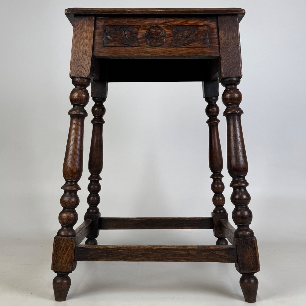 An antique dark oak side table featuring carved rosette apron details, turned legs, and lower stretchers. View V