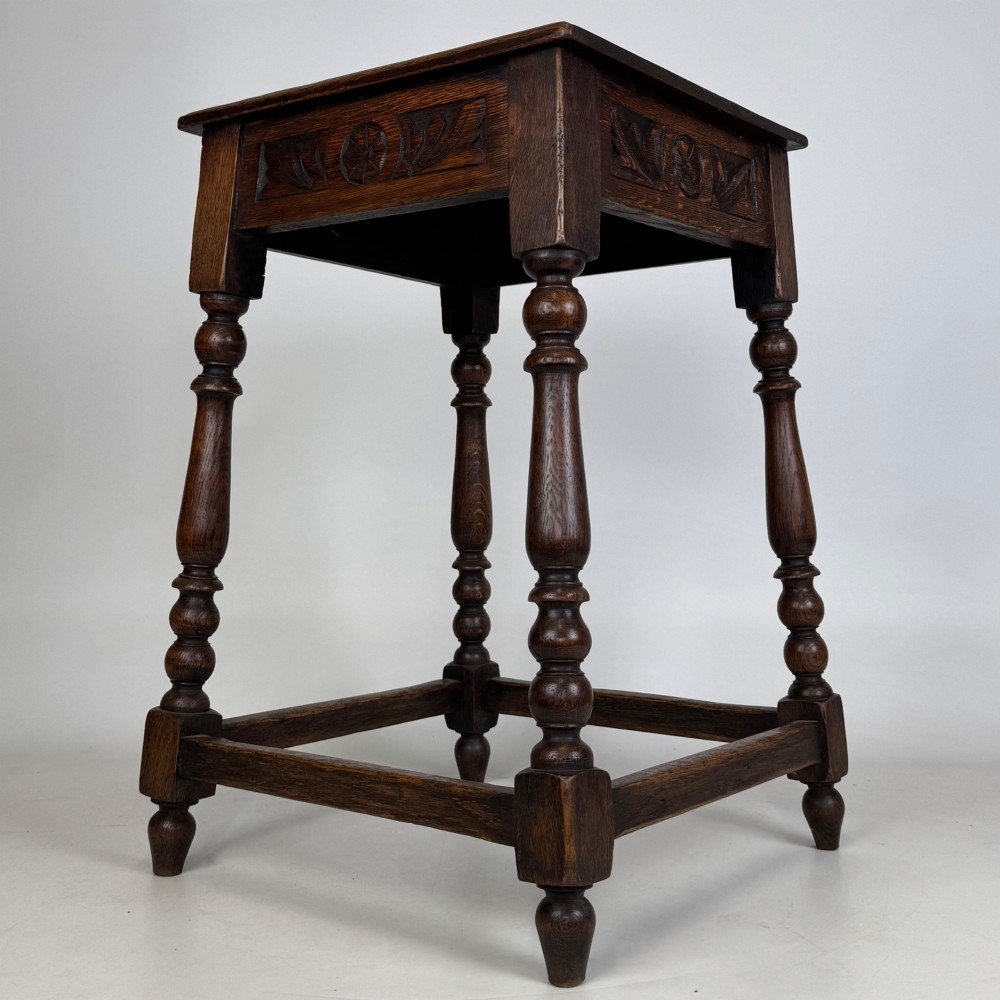 An antique dark oak side table featuring carved rosette apron details, turned legs, and lower stretchers. View VI