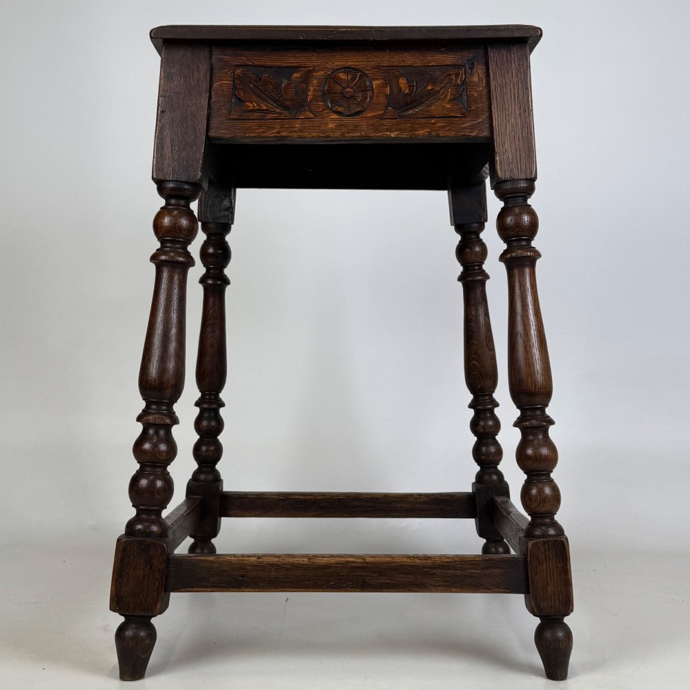 An antique dark oak side table featuring carved rosette apron details, turned legs, and lower stretchers. View VII