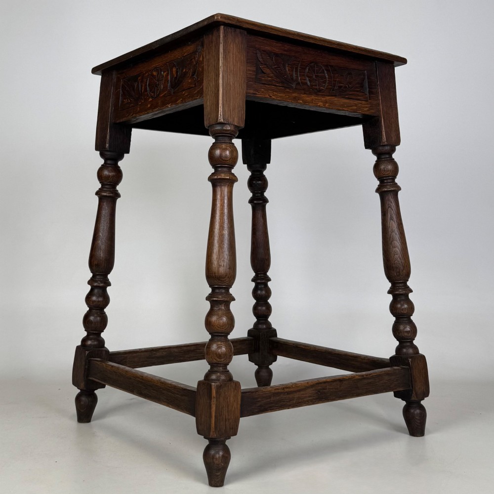 An antique dark oak side table featuring carved rosette apron details, turned legs, and lower stretchers. View VIII