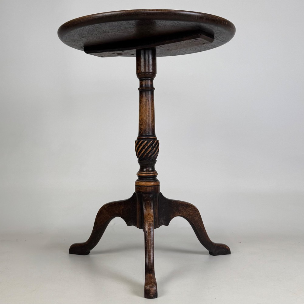 A 19th-century dark oak circular side table featuring a turned pedestal with spiral carving on a tripod base.