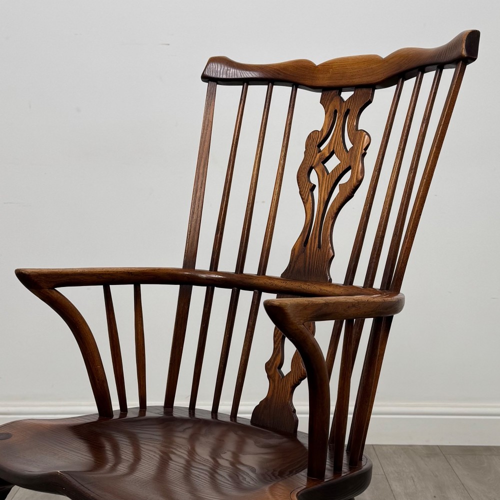 A pair of warm brown elm Windsor armchairs featuring shaped top rails, pierced back splats, spindle supports, shaped saddle seats, and front cabriole legs. View X