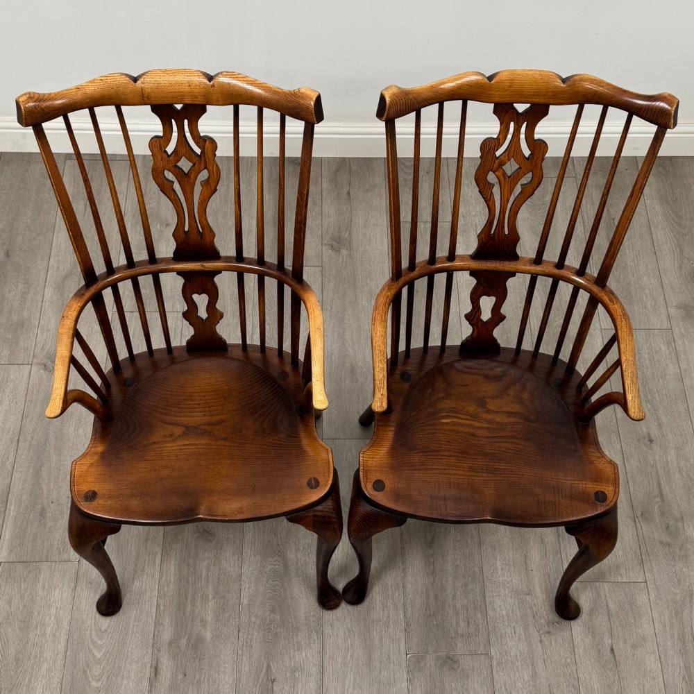 A pair of warm brown elm Windsor armchairs featuring shaped top rails, pierced back splats, spindle supports, shaped saddle seats, and front cabriole legs. View XIV