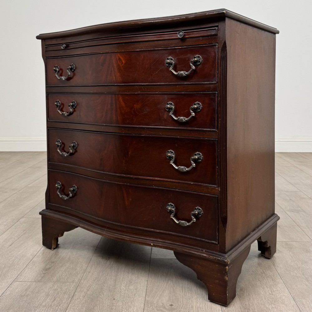 A mahogany serpentine-front chest of drawers featuring four graduated drawers with brass handles and bracket feet. View II