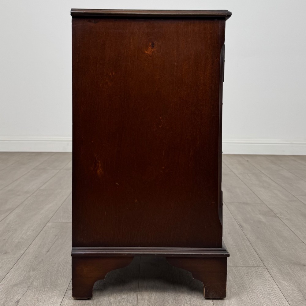 A mahogany serpentine-front chest of drawers featuring four graduated drawers with brass handles and bracket feet. View VII