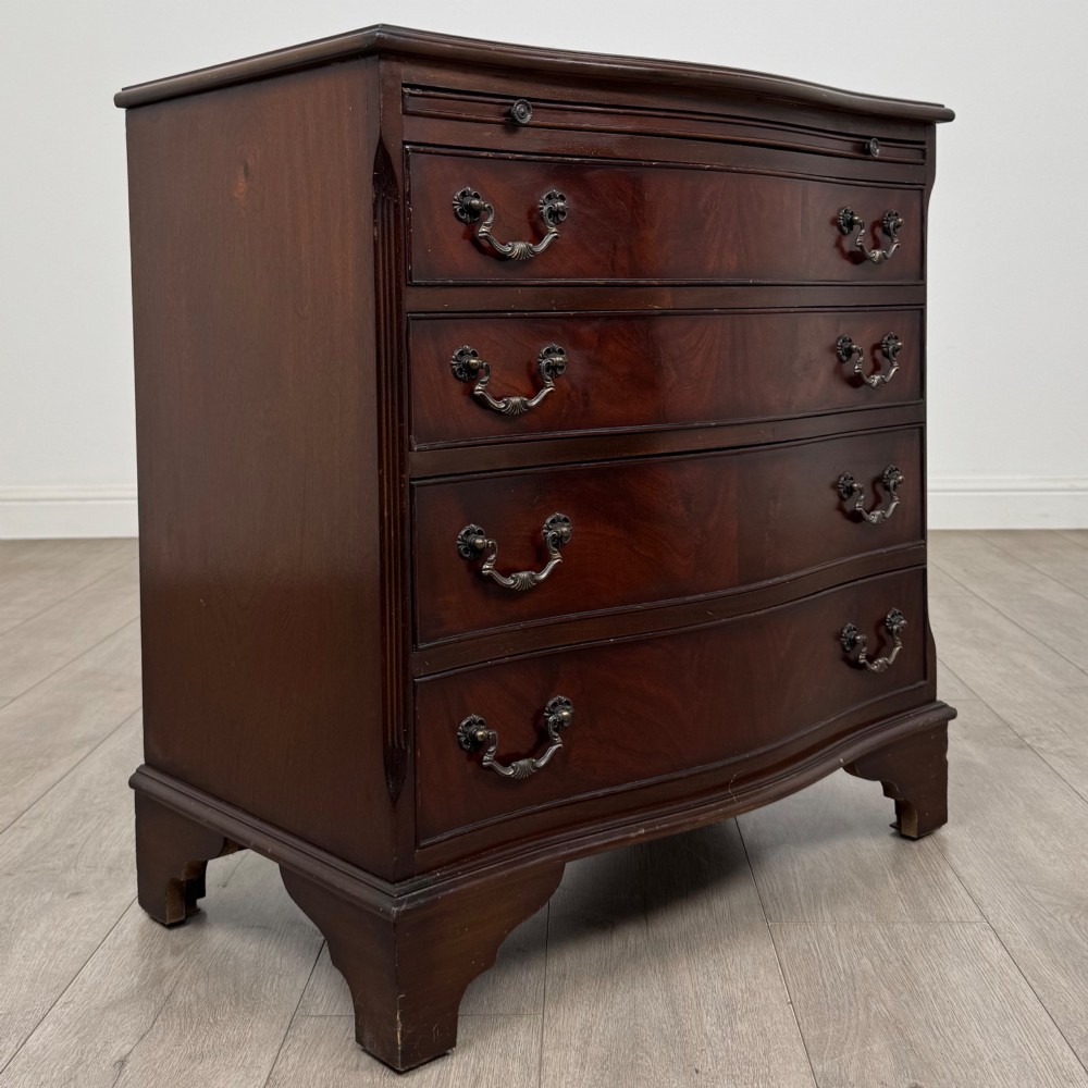 A mahogany serpentine-front chest of drawers featuring four graduated drawers with brass handles and bracket feet. View VIII