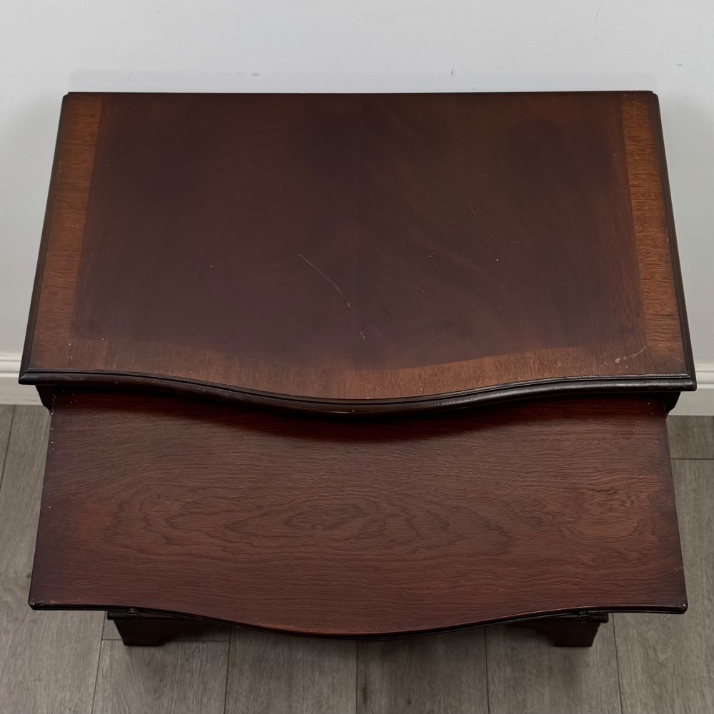 A mahogany serpentine-front chest of drawers featuring four graduated drawers with brass handles and bracket feet. View X