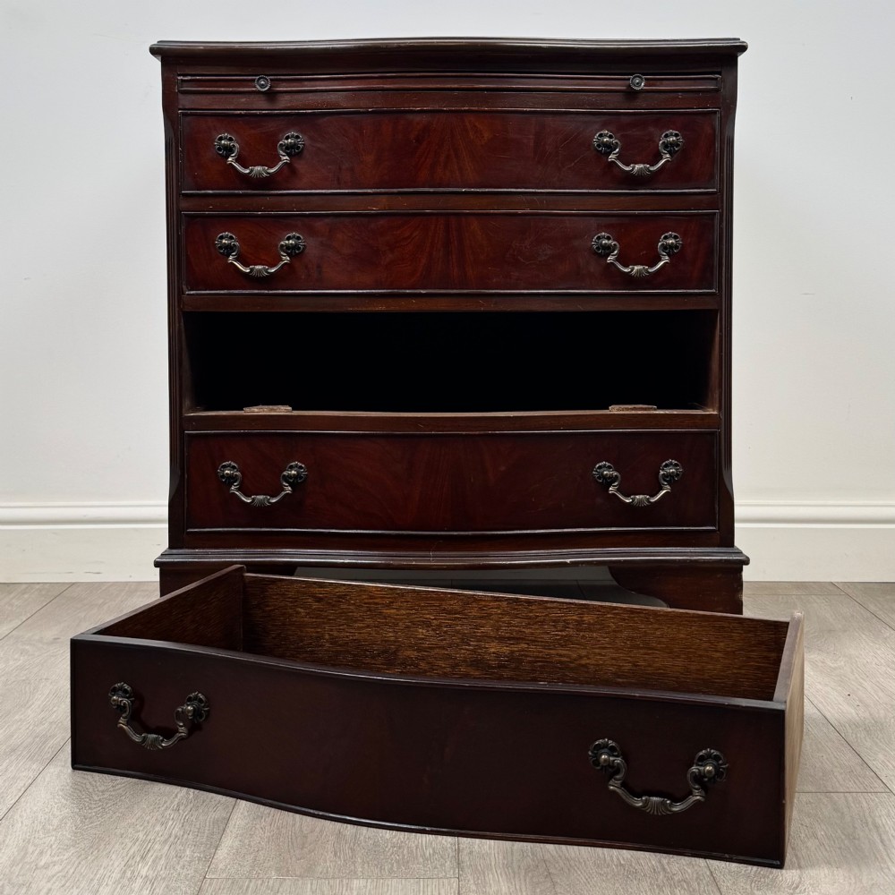 A mahogany serpentine-front chest of drawers featuring four graduated drawers with brass handles and bracket feet. View XI