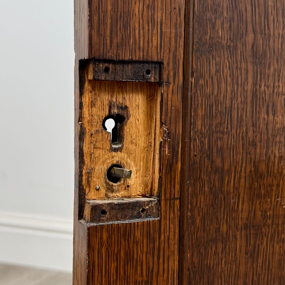 An early 20th-century oak Arts and Crafts sideboard featuring hand-carved foliate panels, copper drop handles, multiple drawers, and a central open recess. View XIII